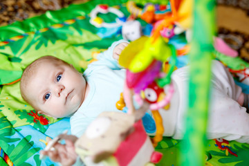 Cute adorable newborn baby playing on colorful toy gym