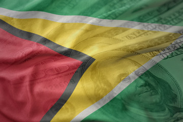 colorful waving national flag of guyana on a american dollar money background. finance concept