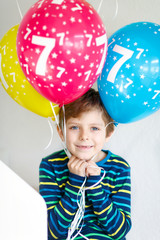 Fototapeta na wymiar Portrait of happy kid boy with bunch on colorful air balloons on 7 birthday