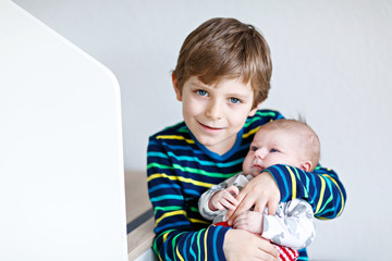 Happy little kid boy with newborn baby sister girl