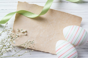 Easter eggs and blank note on wooden background, pastel colors, top view
