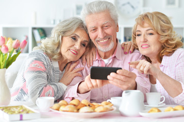 Obraz na płótnie Canvas Elderly people having breakfast and using mobile phone