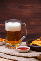 Glass of beer. Nachos chips. Tortilla snack. Mexican salsa nuts. Appetizer with sweet salsa or chilli sauce. Mug or pint of ale. On rustic wooden background.