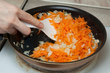 onions and carrots in a hot frying pan - 140952670