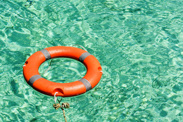 Lifebuoy tied with rope in flickering clear green sea water. Safety equipment for snorkel diving activity.