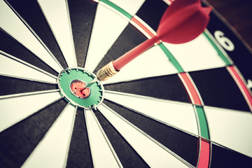 Dart arrow hitting in the target center of dartboard