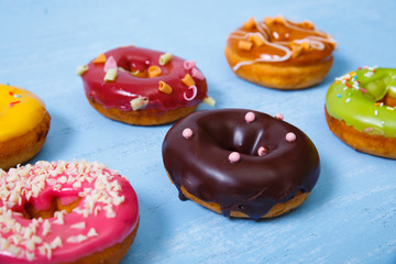 Donuts with icing. Sweet glazed donut. Dessert with sprinkles. On blue wooden rustic background.