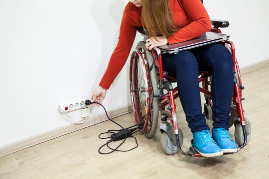 Disabled Caucasian woman has some issues when inserts power plug. Wheel chair sitting