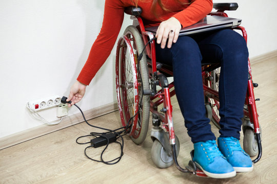 Caucasian female hand stretching to power socket in wall. Disabled woman in wheelchair