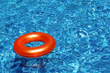 Orange pool float, ring floating in a refreshing blue swimming pool