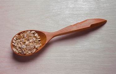 Dry rolled oatmeal in wooden spoon.