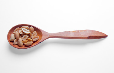Peeled peanuts in a wooden spoon, isolated on a white background