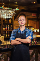 Barman at work in pub,Portrait of cheerful barman worker standing,Waiter giving menus,A pub.Bar.Restaurant.Classic.Evening.European restaurant.European bar.American restaurant.American bar.