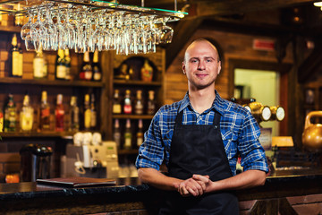 Barman at work in pub,Portrait of cheerful barman worker standing,Waiter giving menus,A pub.Bar.Restaurant.Classic.Evening.European restaurant.European bar.American restaurant.American bar.