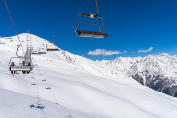 Fototapeta na wymiar Sessellift an einem verschneiten Berghang mit blauem Himmel