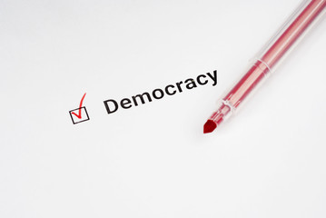 Questionnaire. Red marker and the inscription democracy with check mark on the white paper