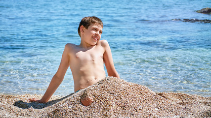 Young beautiful european caucasian boy plays on beach sand pebble sea Montenegro Boka kotorska