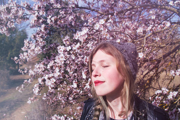 Chica joven disfrutando del aroma de las flores en primavera