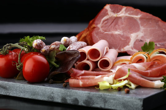 Food tray with delicious salami, pieces of sliced ham, sausage, tomatoes, salad and vegetable - Meat platter with selection