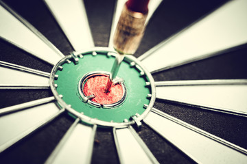 Dart arrow hitting in the target center of dartboard