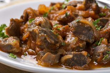 Close up of chicken gizzard stew on plate with herbs