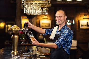 Bartender pouring the fresh beer in pub,barman hand at beer tap pouring a draught lager beer,beer from the tap,Filling glass with beer,fresh beer,pub.Bar.Restaurant.European bar.American bar.