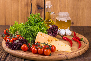 Cheese with fresh vegetables on a wooden background