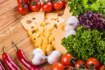 Cheese with fresh vegetables on a wooden background