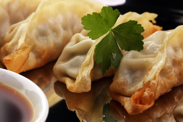 A plate of Japanese gyoza dumplings sitting on a rustic wooden table.