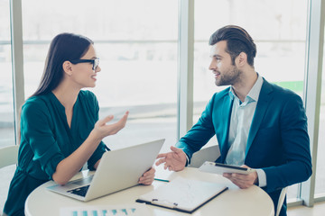 Fototapeta premium Two young businesspeople sitting at the table and actively discussing their new project