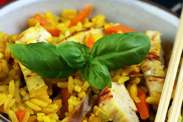 Homemade Chinese fried rice with vegetables, chicken and fried eggs served on a plate with chopsticks