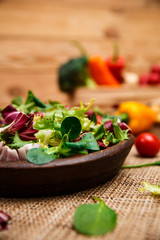 Provence mix salad. Leaves of endive or chicory, lamb and rose salad. Raw vegetables. On wooden table.