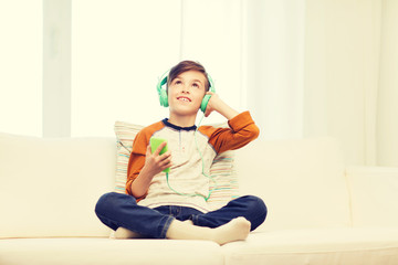 happy boy with smartphone and headphones at home