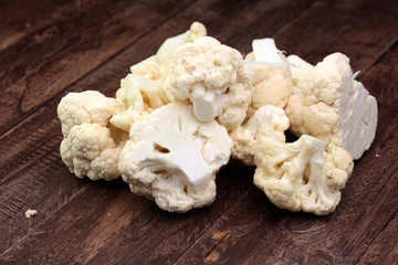 Fresh organic cauliflower cut into small pieces on wooden background