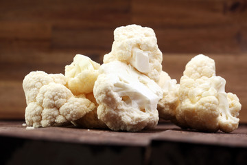 Fresh organic cauliflower cut into small pieces on wooden background