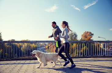 happy couple with dog running outdoors