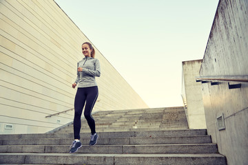 happy sporty woman running downstairs in city