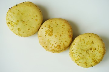 Green round macaron cookies with pistachio on a white platter
