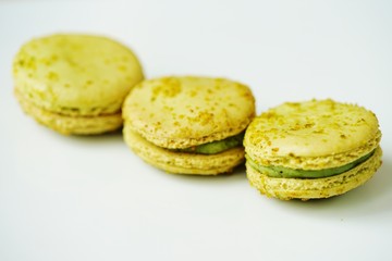 Green round macaron cookies with pistachio on a white platter