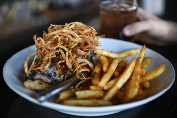 Person sitting at bar holding cocktail, bowl of food on bar