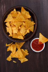 Nachos chips. Delicious salty tortilla with sweet salsa or chilli sauce on wooden background. Snack on rustic plate.