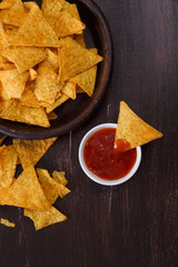 Nachos chips. Delicious salty tortilla with sweet salsa or chilli sauce on wooden background. Snack on rustic plate.