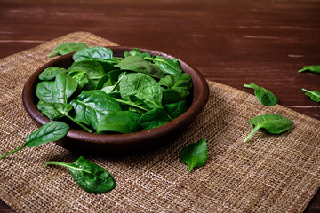 Spinach leaves in bowl. Raw fresh vegetable. Fresh natural plant leaf. Organic bio food on rustic wooden table.