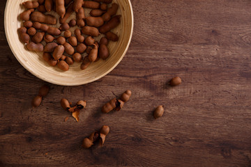 Sweet tamarind on grunge rustic wood background. Natural organic diet food with a lot of vitamins. Plate dish or bowl on wooden board.