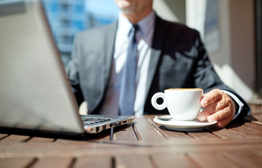 senior businessman with laptop and coffee outdoors