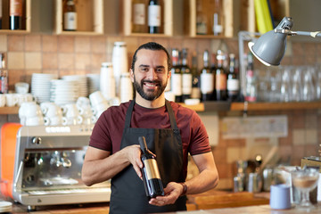 happy man or waiter with bottle of red wine at bar