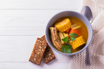 Puchero soup with corn and parsley on wooden table