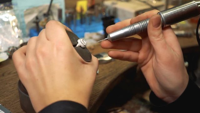 Goldsmith drill a silver ring using a special tool on the table