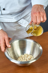 The cook pours olive oil into a bowl full of recipes for food