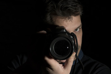 Young man as a photographer portrait isolated on black background